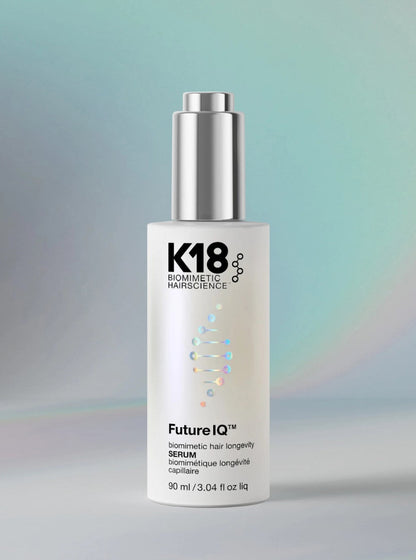 K18 Sommetic Hairscience FutureIQ Serum bottle, 90 ml, featuring a white cylindrical body with a metallic silver pump dispenser, set against a soft, iridescent teal and gray background.