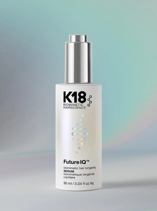 K18 Sommetic Hairscience FutureIQ Serum bottle, 90 ml, featuring a white cylindrical body with a metallic silver pump dispenser, set against a soft, iridescent teal and gray background.