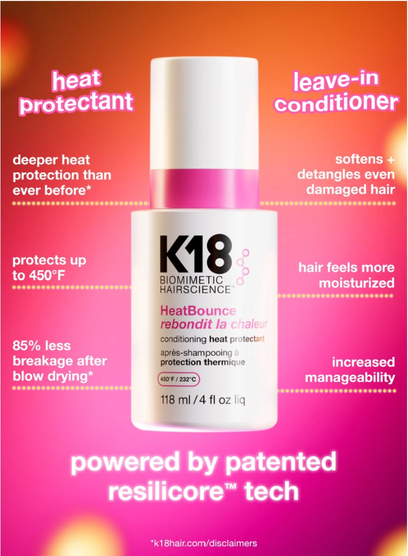A bottle of K18 Biomimetic Hairscience HeatBounce leave-in conditioner is centered on a bright pink-to-orange gradient background with marketing text around it. The bottle is white with a pink cap band and black text.