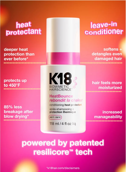 A bottle of K18 Biomimetic Hairscience HeatBounce leave-in conditioner is centered on a bright pink-to-orange gradient background with marketing text around it. The bottle is white with a pink cap band and black text.