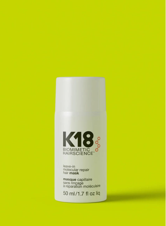 A white cylindrical bottle of K18 Leave-in Molecular Repair Hair Mask, featuring black text and a small orange graphic, set against a solid lime green background.