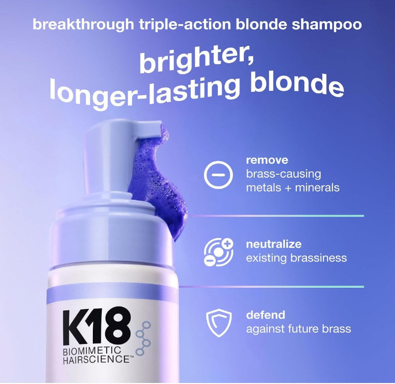 K18 Biomimetic Hairscience breakthrough triple-action blonde shampoo bottle with a pump dispenser and a purple shampoo smear, set against a blue gradient background with product benefits listed on the right.