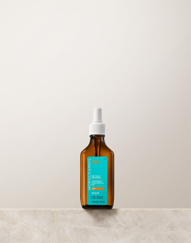 Brown glass bottle with a white cap on a light beige background. This haircare product belongs to Moroccanoil dry scalp treatement 