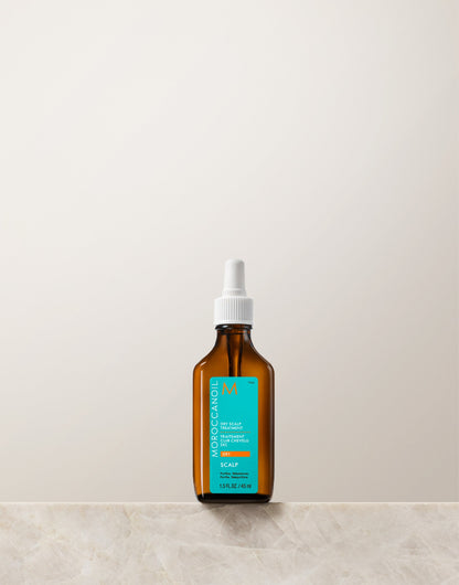 Brown glass bottle with a white cap on a light beige background. This haircare product belongs to Moroccanoil dry scalp treatement 