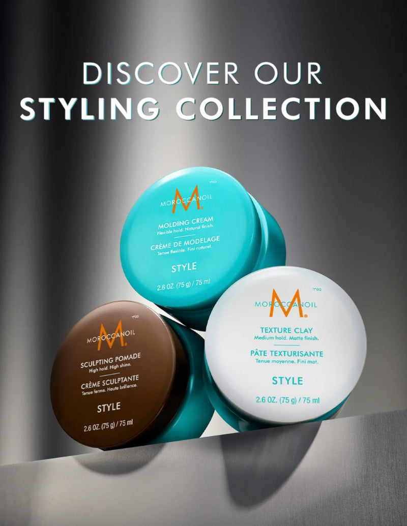Three hair styling products from Moroccano Oil are arranged on a reflective dark surface with large text reading 'DISCOVER OUR STYLING COLLECTION' above them. The products are a turquoise molding cream, a brown sculpting pomade, and a white texture clay, each with the Moroccano Oil 'M' logo visible on the lids.