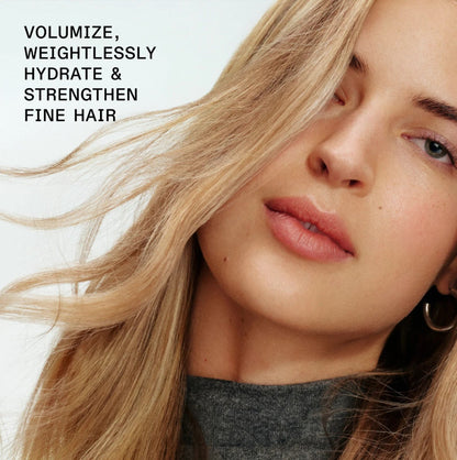 Close-up of a woman with long blonde hair wearing a gray top, with text in the upper left reading 'VOLUMIZE, WEIGHTLESSLY HYDRATE & STRENGTHEN FINE HAIR'.