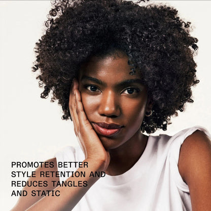 a model with curly hair using Olaplex hair serum that promotes better style retention and reduces tangles and static