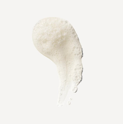 Close-up of a white volumizing Olaplex shampoo drop smear on a light gray background