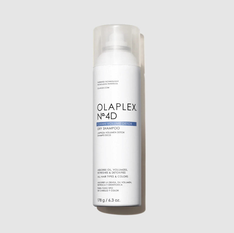 A white bottle of Olaplex No.4D Dry Shampoo with a clear cap, centered on a light gray background.