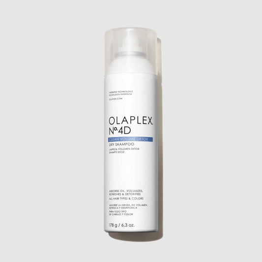 A white bottle of Olaplex No.4D Dry Shampoo with a clear cap, centered on a light gray background.