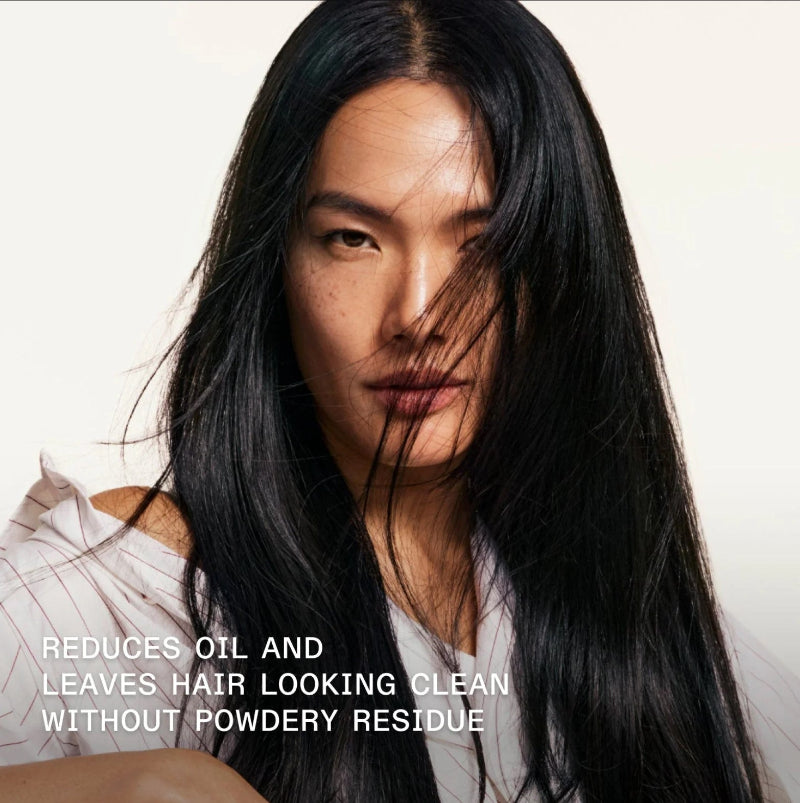 Woman with long dark hair against a plain background with text about Olaplex hair care product benefits reducing oil without powdery residue.