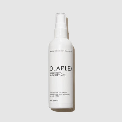 A white plastic spray bottle of Olaplex Volumizing Blow Dry Mist on a light gray background.