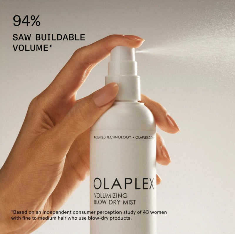 Olaplex volumizing blow dry mist bottle held by a hand with text about buildable volume.