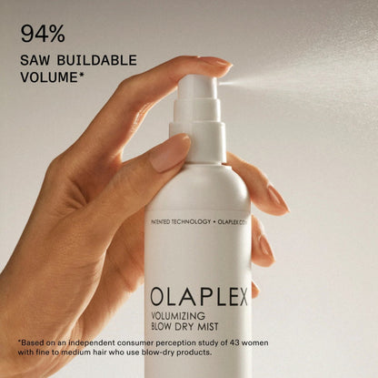Olaplex volumizing blow dry mist bottle held by a hand with text about buildable volume.