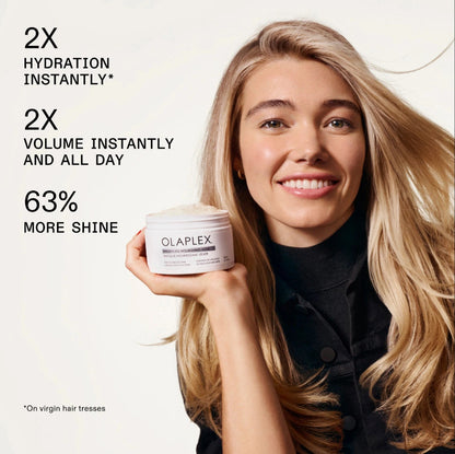 Woman holding a jar of Olaplex with product benefits text on a white background mentioning 2 times more hydration instantly, 2 times more volume instantly, and more shine 