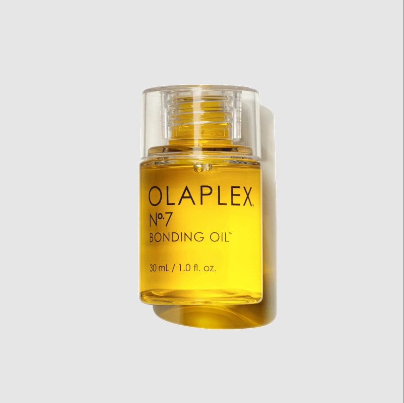 A bottle of Olaplex No. 7 Bonding Oil small size with golden-yellow liquid inside a clear glass container, set against a light gray background with a soft shadow.