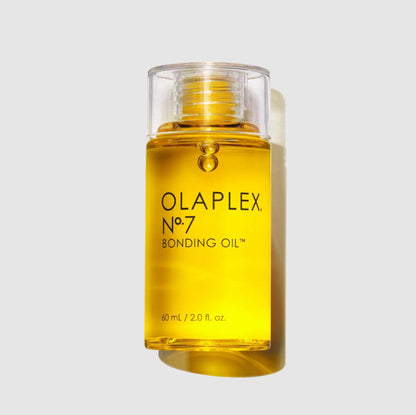 A bottle of Olaplex No. 7 Bonding Oil filled with golden yellow liquid, set against a light gray background with a soft shadow.