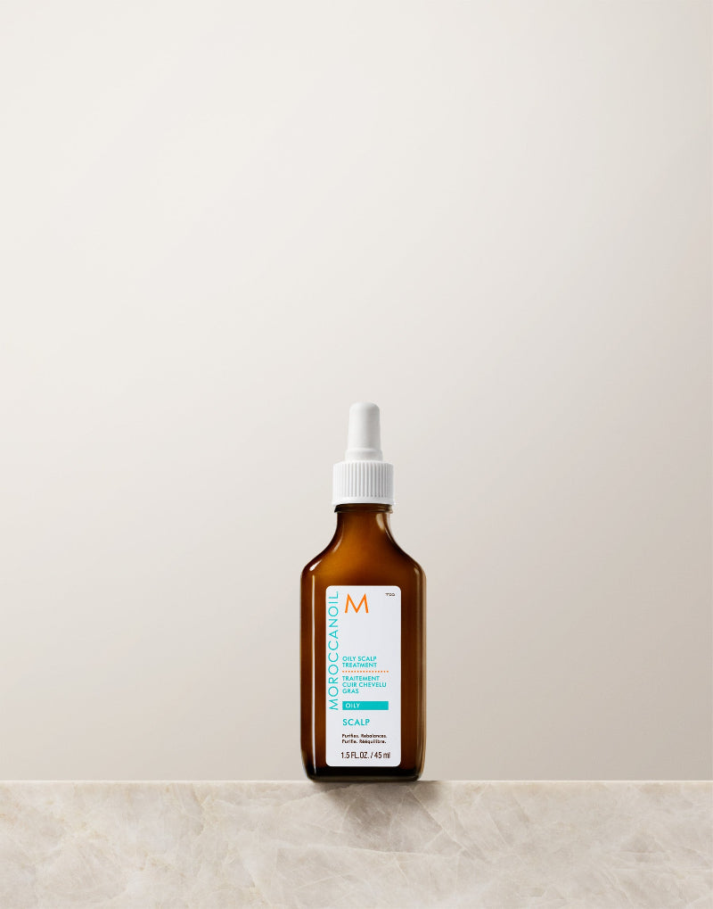 Brown bottle of Moroccanoil oily scalp treatment with white cap on a light beige background