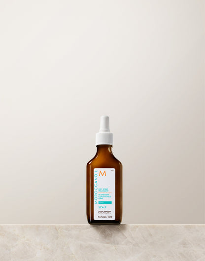 Brown bottle of Moroccanoil oily scalp treatment with white cap on a light beige background