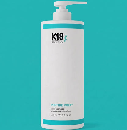 A tall white pump bottle of K18 Biodynamic Haircare Peptide Prep shampoo, featuring a clean white label with teal and black text, set against a solid teal background. The best value size only at Sassy hair Canada